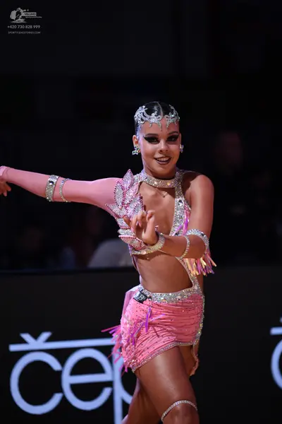 Dancesport competitor: Female dancer: pink latin dance costume with sequins and fringe, including a mat