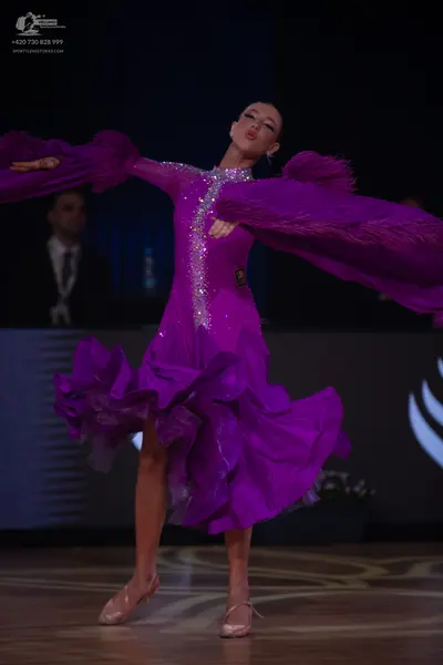 Dancesport competitor: Female dancer: purple latin dress with large ruffles on the sleeves and skirt, f