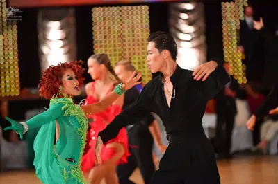 Dancesport competitor: Female dancer: green Latin dance dress with long sleeves, matching gloves, and s
