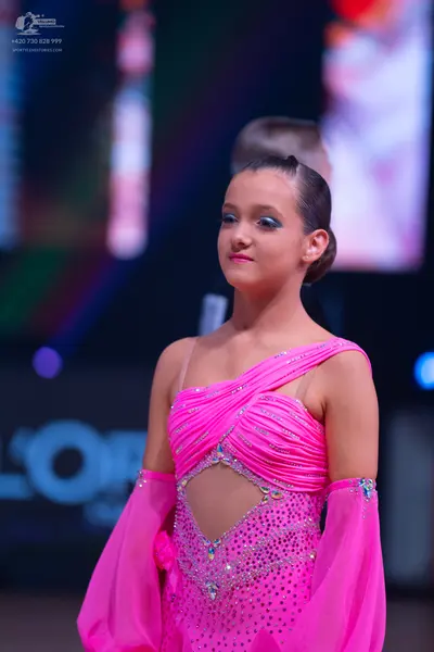 Dancesport competitor: Female dancer: bright pink latin dance dress with one-shoulder design, sequin an