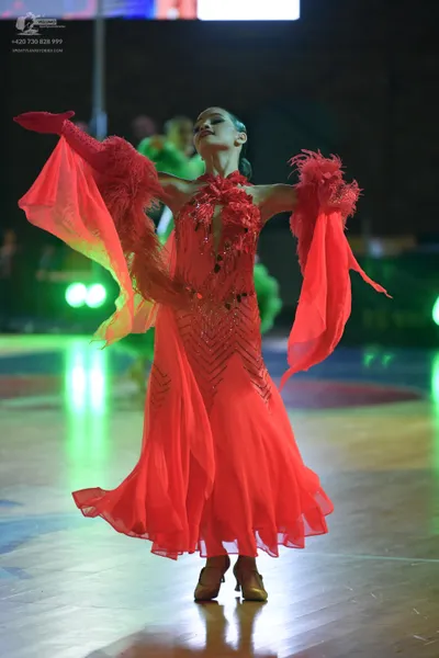 Dancesport competitor: Female dancer: red latin dress with sequined patterns on the bodice, red feather