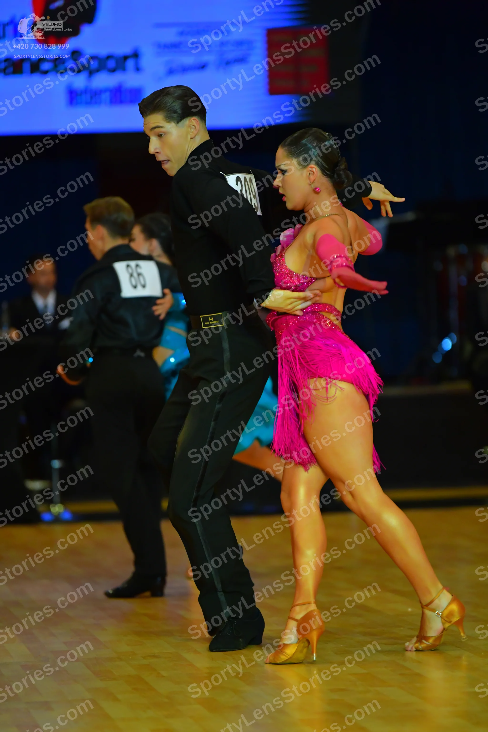 Dancesport competitor #86, #209: Male dancer in foreground: black long-sleeved shirt and black trousers