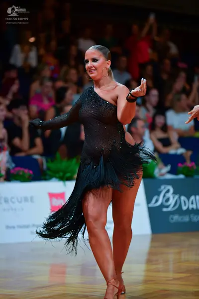 Dancesport competitor: Female dancer: black one-shoulder Latin dress with small embellishments and long