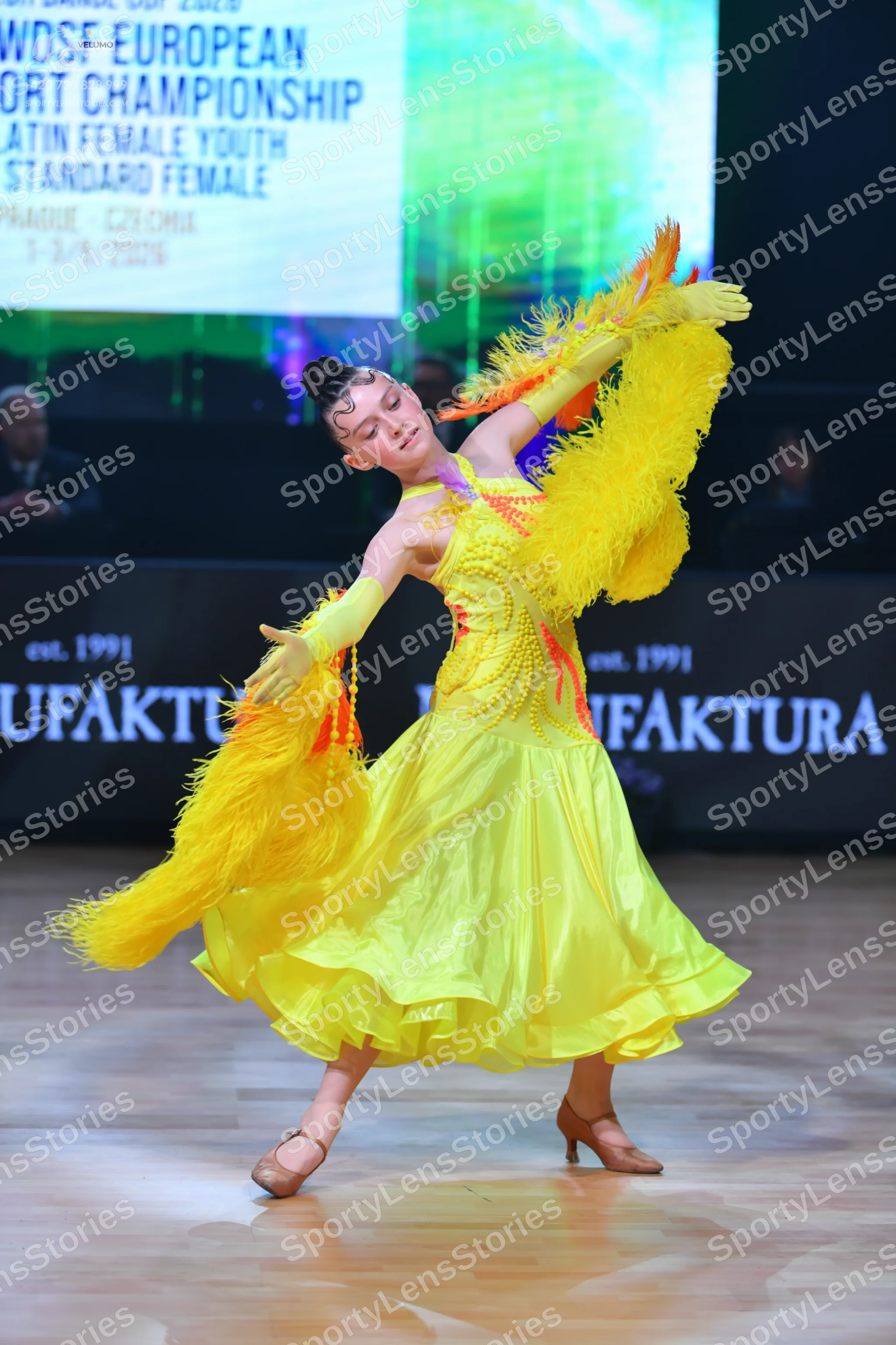 Dancesport competitor: Female dancer: bright yellow ballroom dress with a sequined bodice and a large,