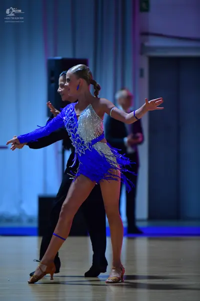 Dancesport competitor: Female dancer: blue and silver latin dress with a sequin bodice, one long sleeve