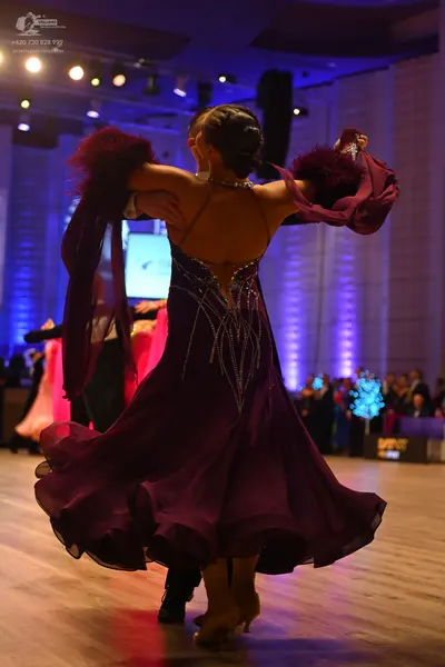 Dancesport competitor: Female dancer: deep purple ballroom dress with silver rhinestone embellishments 