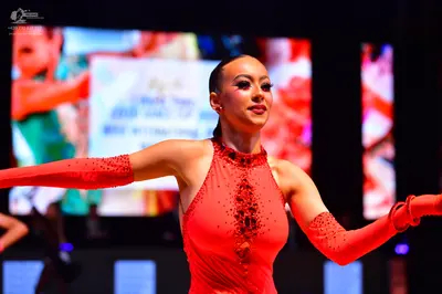 Dancesport competitor: Female dancer: red Latin dance dress with sequins and long sleeves