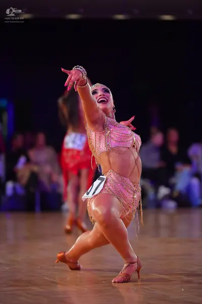 Dancesport competitor #145: Female dancer in foreground: nude-colored Latin costume heavily embellished with