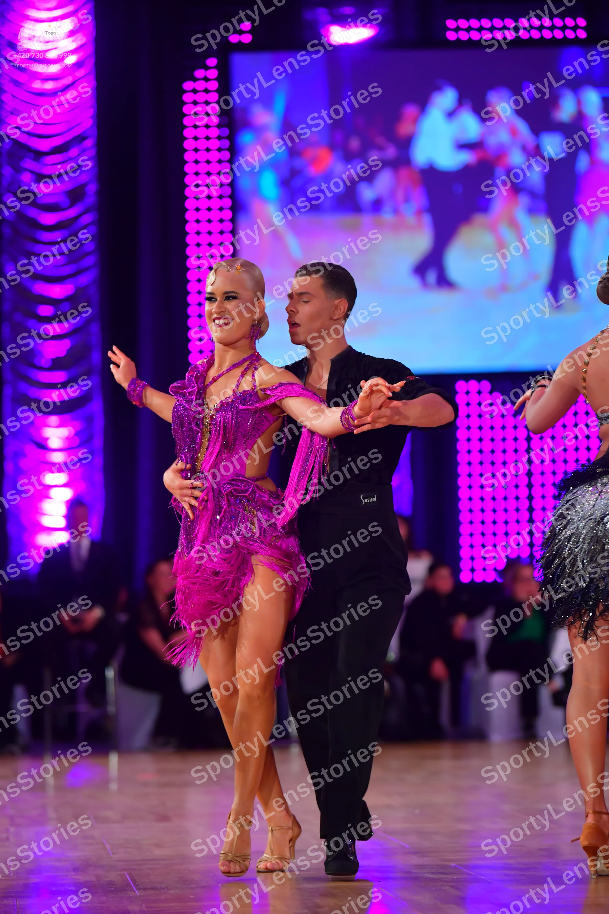 Dancesport competitor: Female dancer: magenta Latin dance dress with sequins and long fringe, and a mat