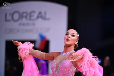 Dancesport competitor: Female dancer: pink latin dress with sequins, rhinestones, large pink feathers o