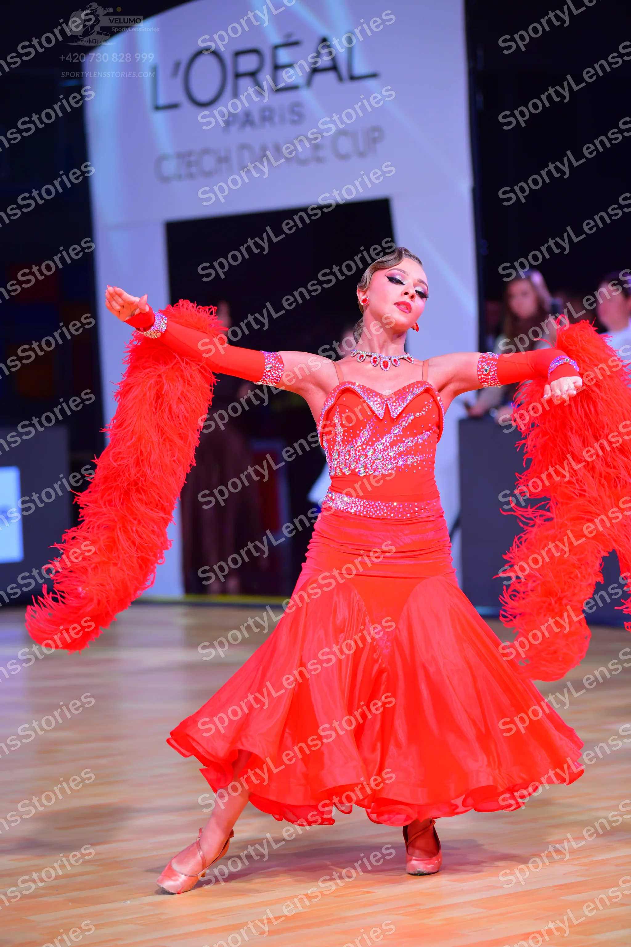 Dancesport competitor: Female dancer: red Latin dress with a sequined bodice, long sleeves, and volumin