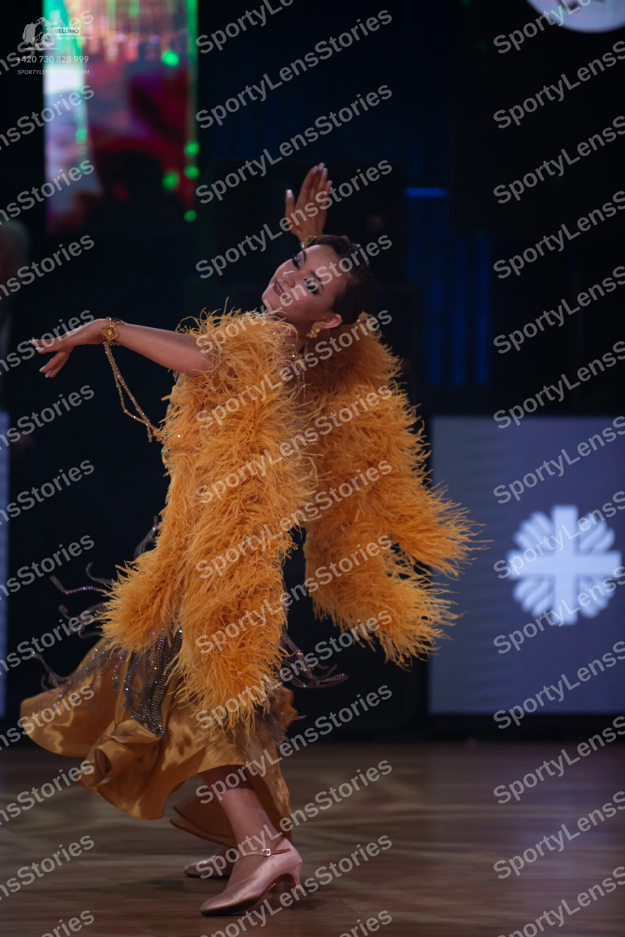 Dancesport competitor: Female dancer: mustard yellow Latin dance dress with voluminous feather embellis