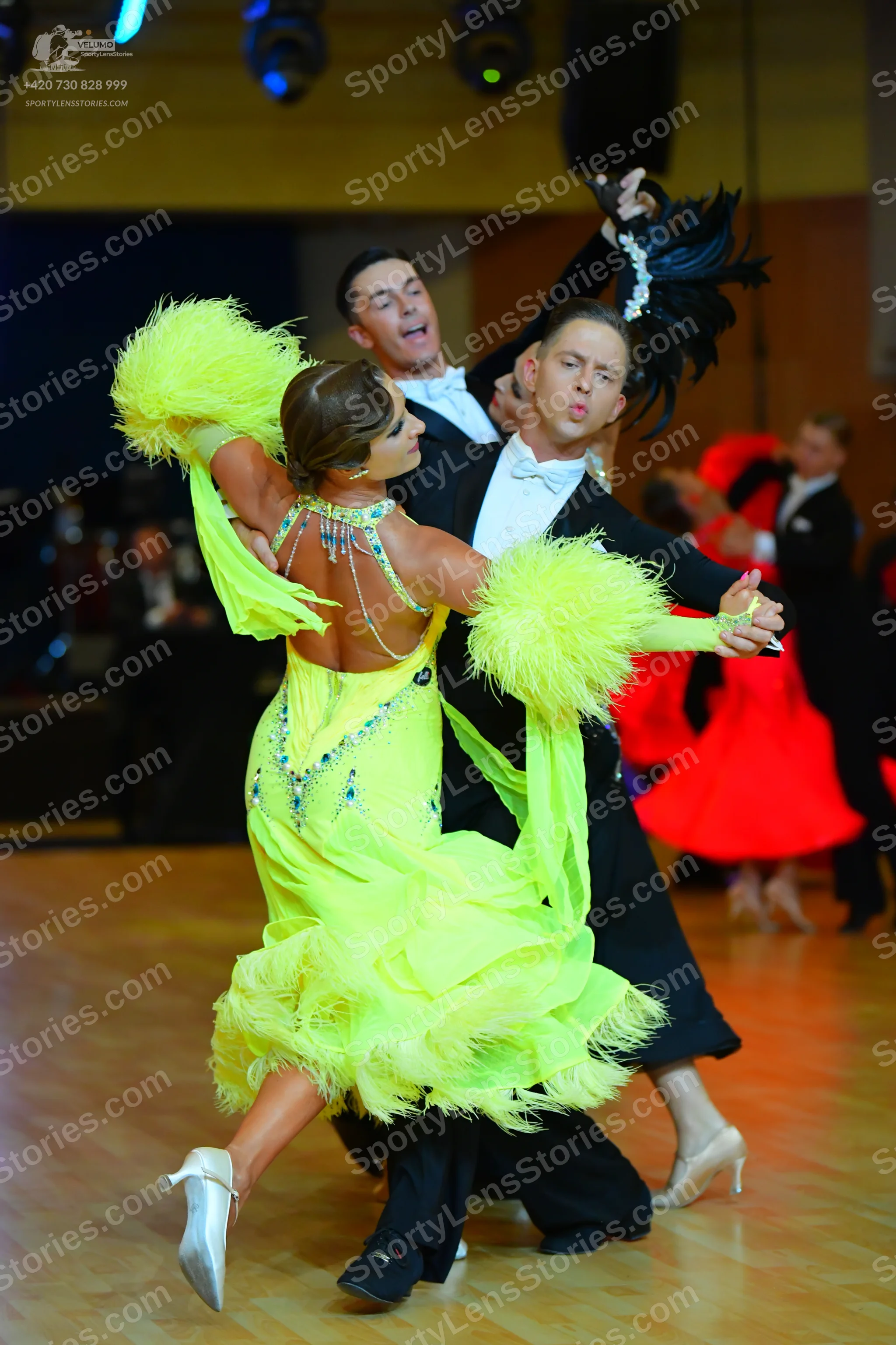 Dancesport competitor: Main female dancer: bright yellow Latin dress with feather trim on the sleeves a