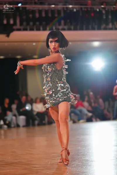 Dancesport competitor: Female dancer: dark mini dress heavily embellished with large silver sequins/pai