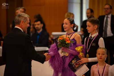 Dancesport competitor: Female dancer: purple dress with feather-like detailing on the sleeves