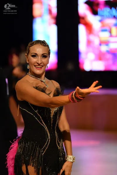 Dancesport competitor: Female dancer: black latin dress with sequins, fringe, and mesh neckline, access
