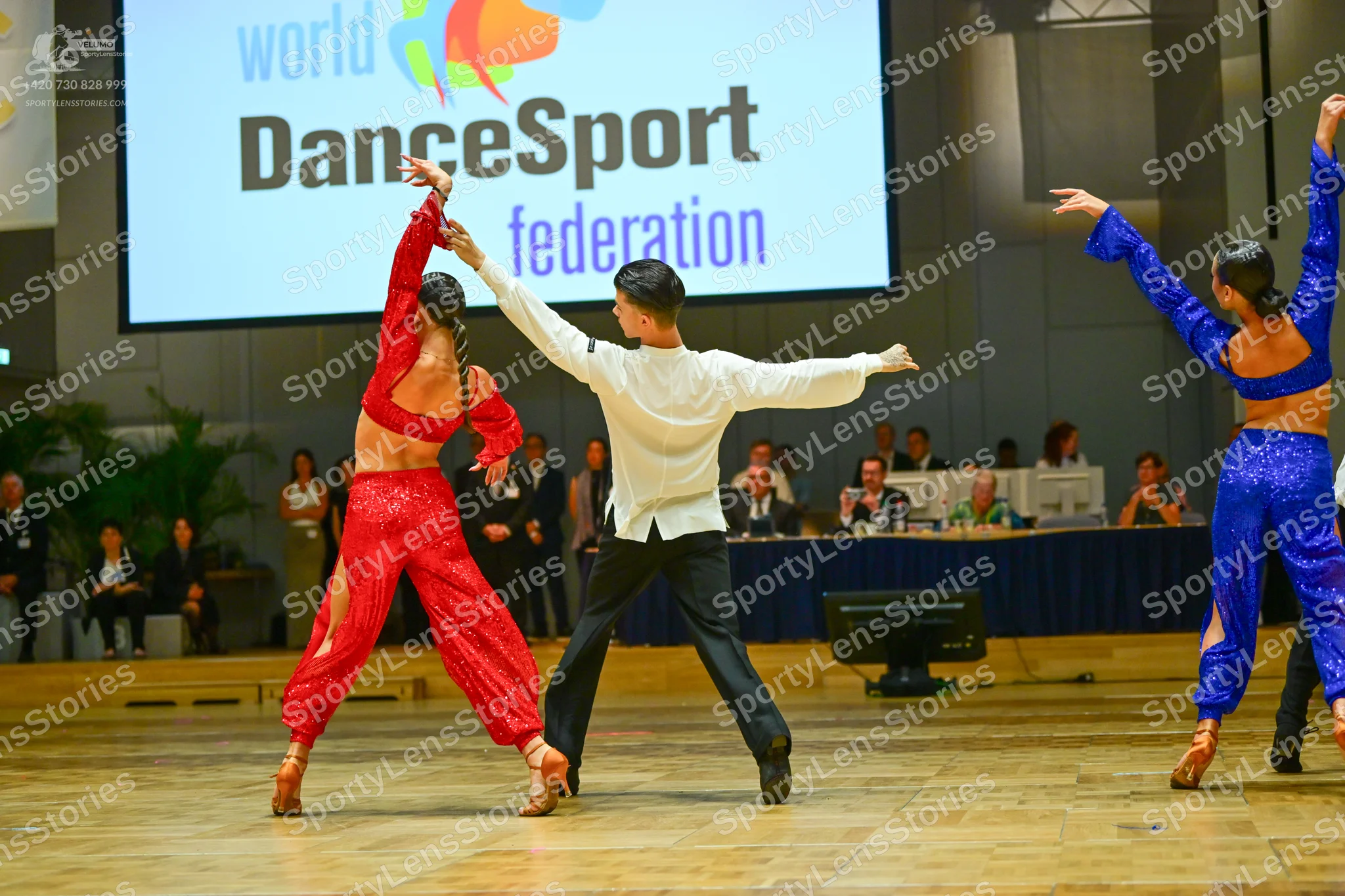 Dancesport competitor: Female dancer (left): red two-piece latin costume with a long-sleeved crop top a