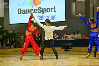 Dancesport competitor: Female dancer (left): red two-piece latin costume with a long-sleeved crop top a
