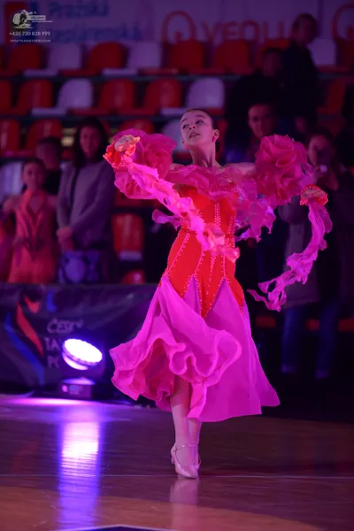 Dancesport competitor: Female dancer: vibrant pink/magenta ballroom dress with large ruffled/flounced s