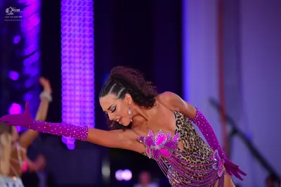 Dancesport competitor: Female dancer in foreground: leopard print latin dress with large purple sequine