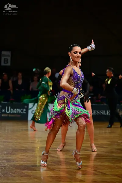 Dancesport competitor: Female dancer in foreground: purple latin dress with a sequined bodice and multi