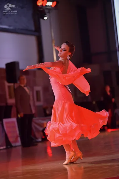 Dancesport competitor: Female dancer: peach-colored ballroom dress with a large, flowing ruffled skirt 