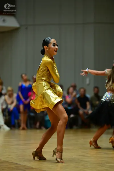 Dancesport competitor: Main female dancer: gold, metallic-finish, long-sleeved Latin dress