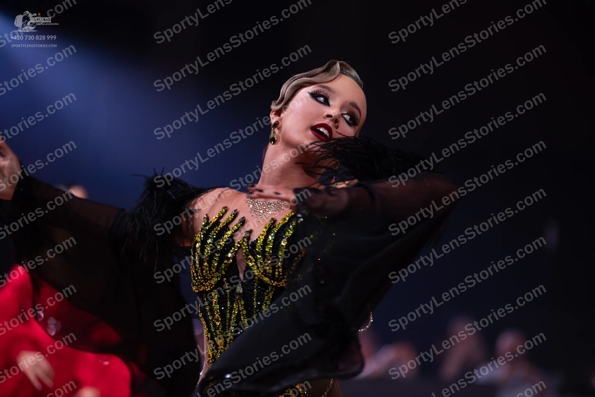 Dancesport competitor: Female dancer: black Latin dance dress with gold and yellow sequin patterns on t