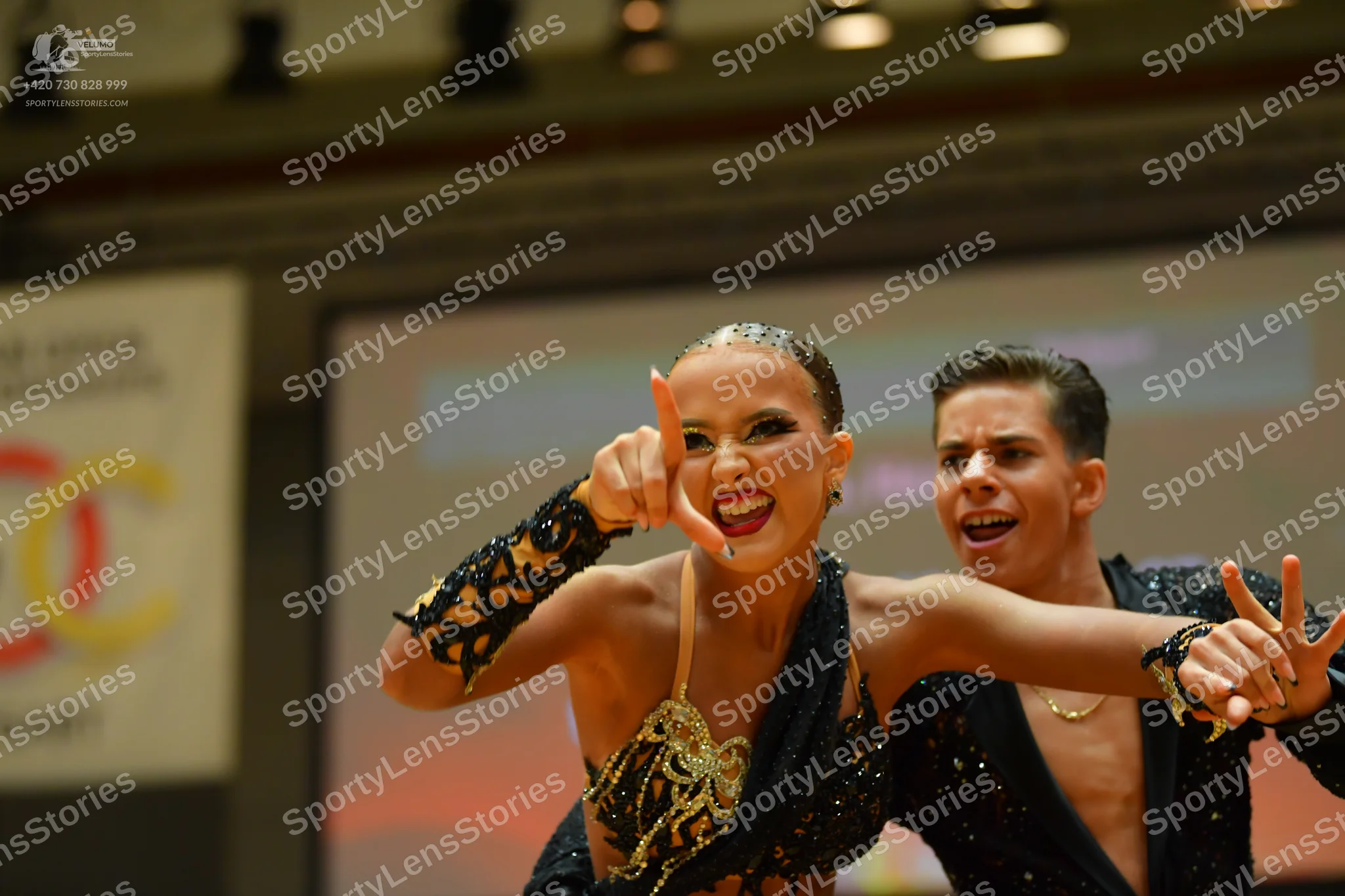Dancesport competitor: Female dancer: black Latin dance costume with intricate gold and yellow sequined