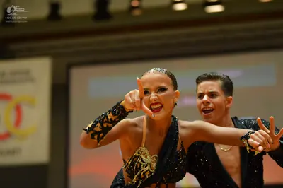 Dancesport competitor: Female dancer: black Latin dance costume with intricate gold and yellow sequined