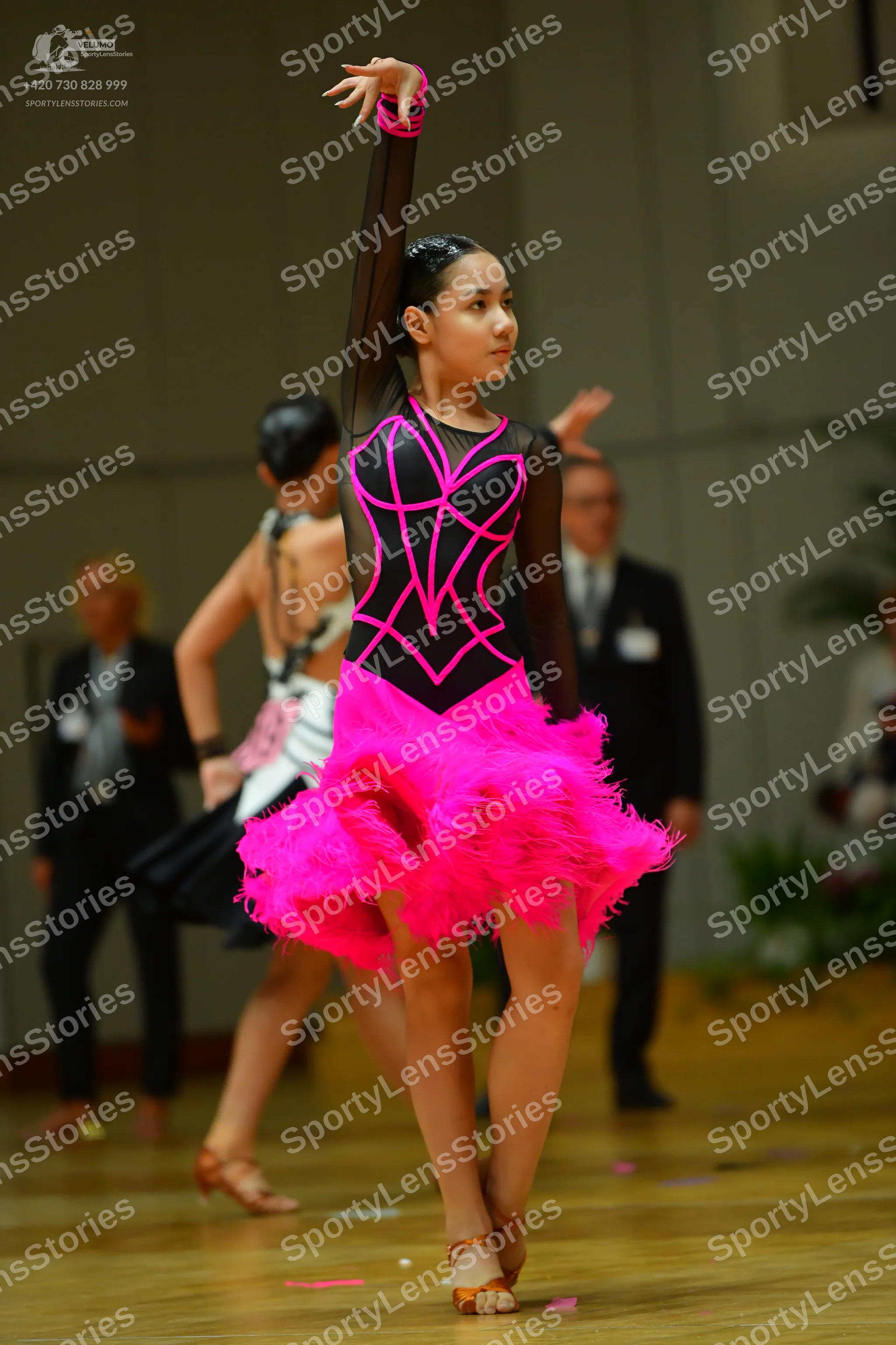 Dancesport competitor: Female dancer: black long-sleeved Latin dress with bright pink neon piping and a