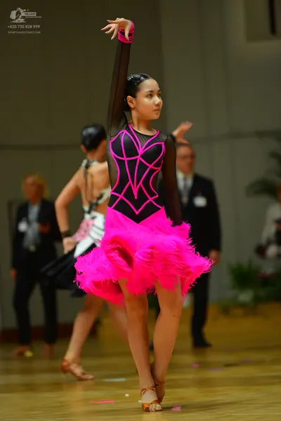 Dancesport competitor: Female dancer: black long-sleeved Latin dress with bright pink neon piping and a
