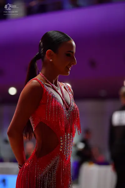 Dancesport competitor: Female dancer: red Latin dress with silver fringe and sequin embellishments
