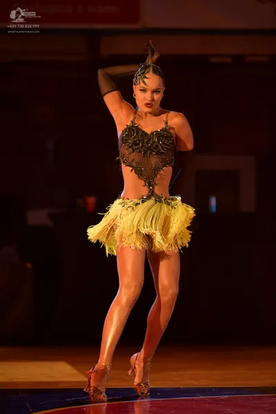 Dancesport competitor: Female dancer: black latin dress with a yellow fringe skirt, featuring a sequine