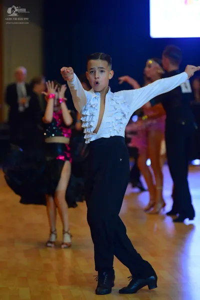 Dancesport competitor: Central male dancer: white long-sleeved shirt with ruffles and black trousers