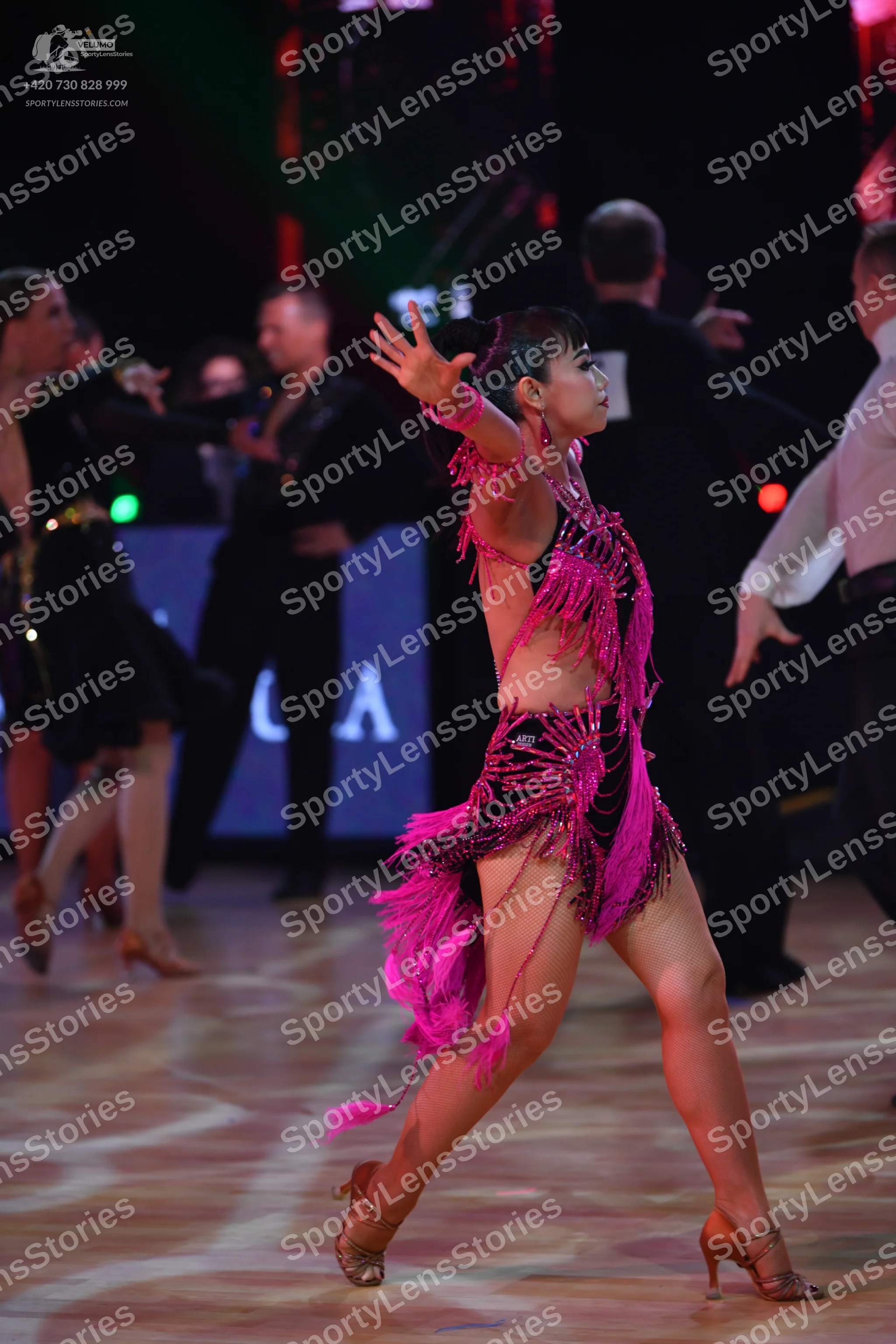 Dancesport competitor: Female dancer in foreground: pink Latin dress with long fringe and sequins