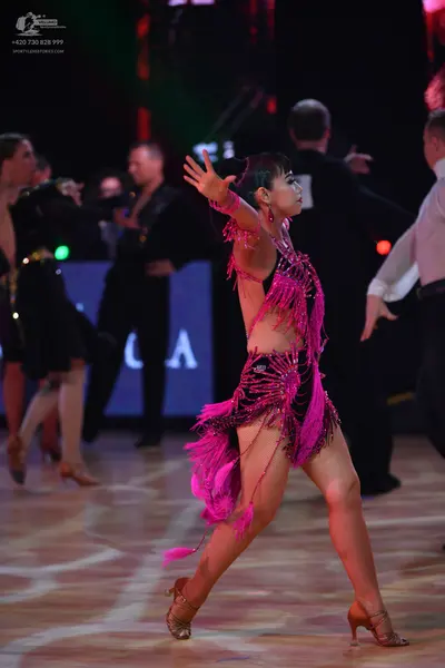 Dancesport competitor: Female dancer in foreground: pink Latin dress with long fringe and sequins