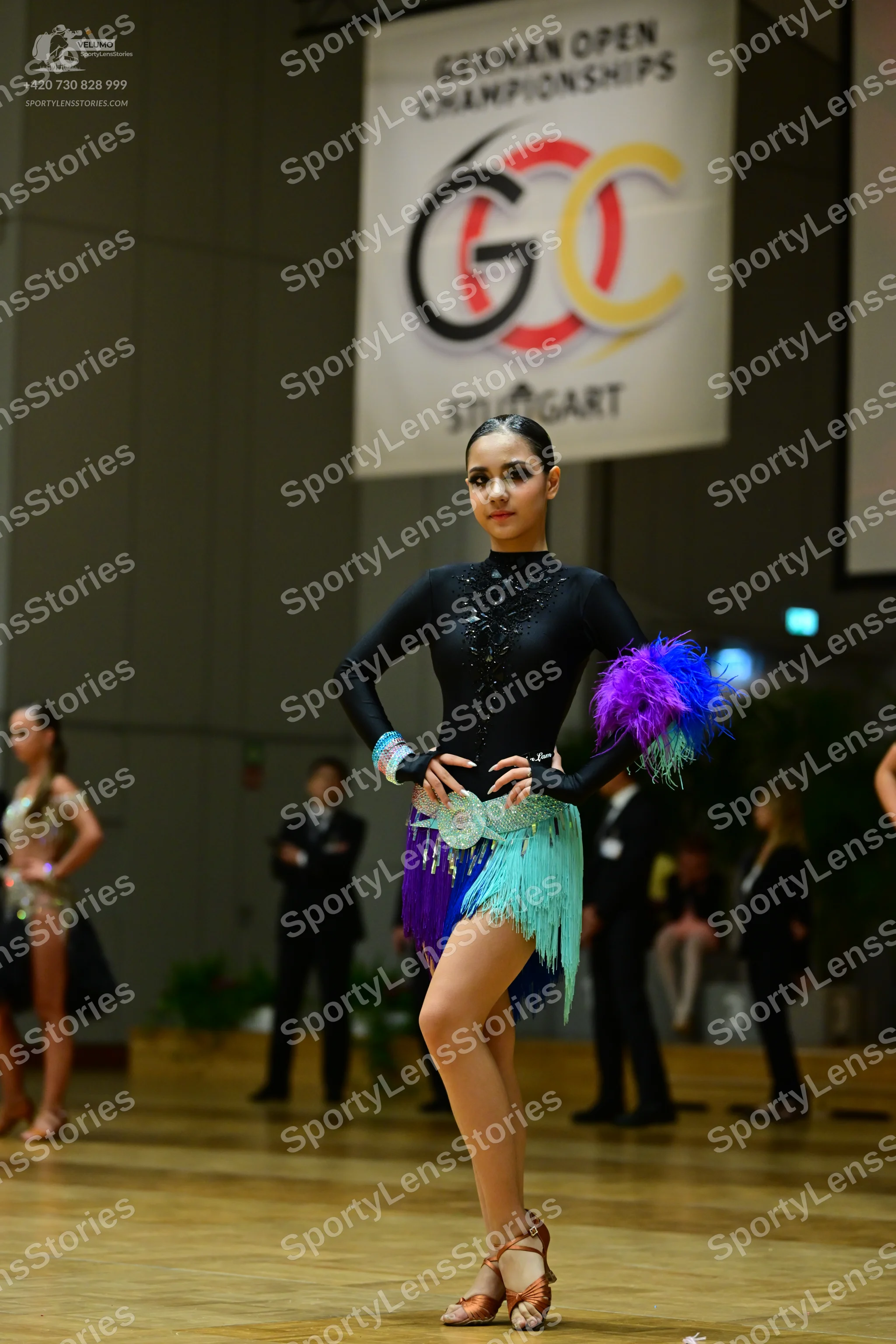 Dancesport competitor: Female dancer (center): black long-sleeved latin dress with a sequined neckline