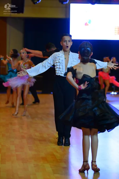 Dancesport competitor: Male dancer: white long-sleeved shirt with ruffles on the front and cuffs, and b
