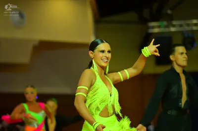 Dancesport competitor: Main female dancer: neon yellow Latin dance dress with fringe, cutouts, and matc
