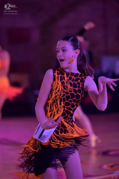 Dancesport competitor: Female dancer in foreground: black and orange latin dress with a honeycomb patte