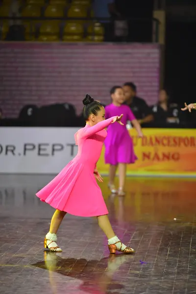 Dancesport competitor: Female dancer in foreground: pink long-sleeved dress with a smooth finish