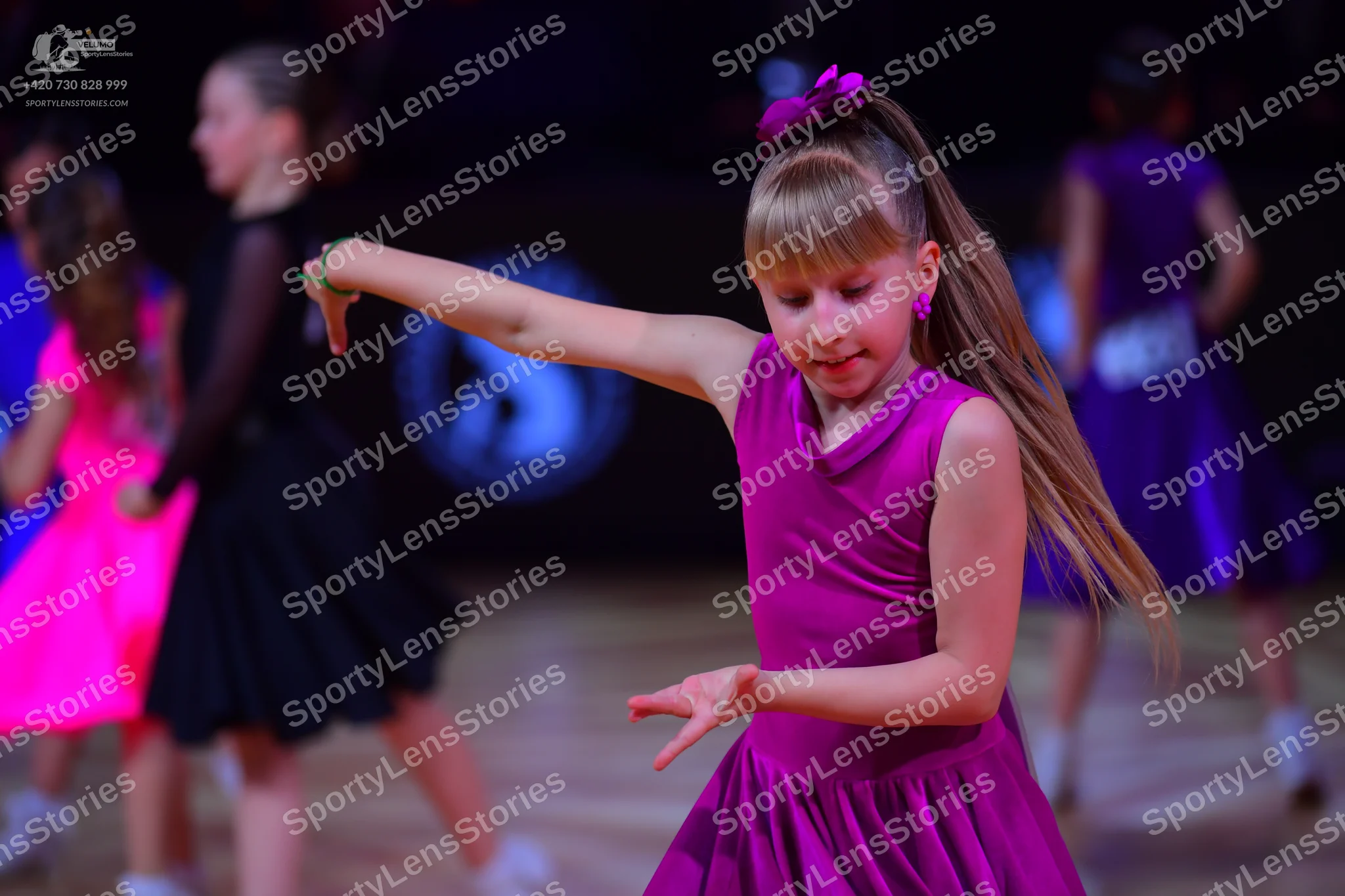 Dancesport competitor: Female dancer in foreground: magenta sleeveless dress with a high neckline and a