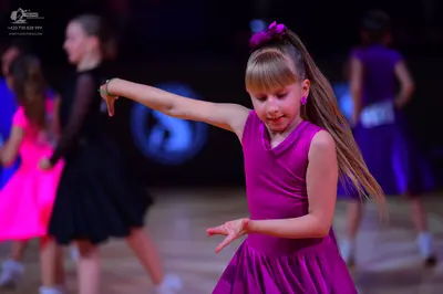 Dancesport competitor: Female dancer in foreground: magenta sleeveless dress with a high neckline and a