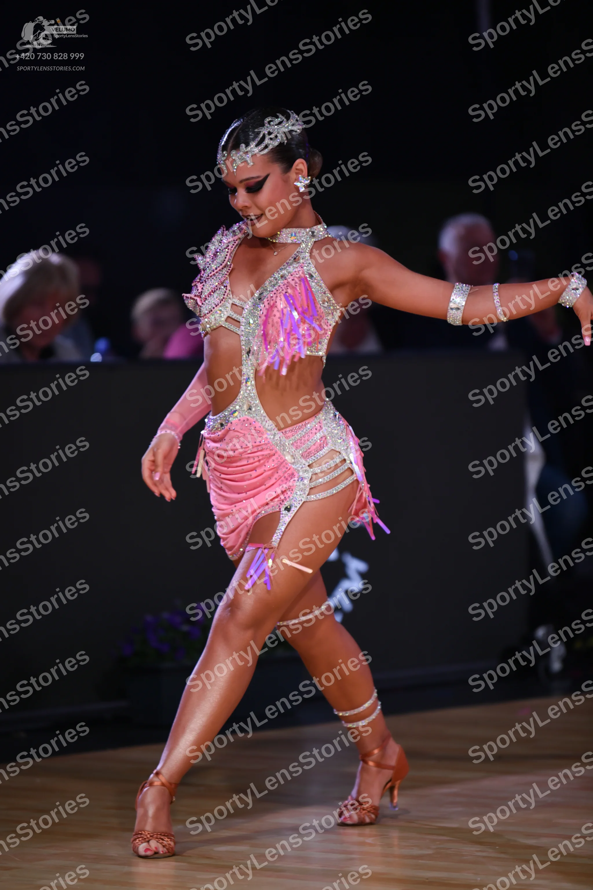 Dancesport competitor: Female dancer: pink Latin costume with sequins, rhinestones, and fringe, accompa
