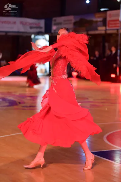 Dancesport competitor: Female dancer: bright red Latin dance dress with a sequined bodice, a multi-laye