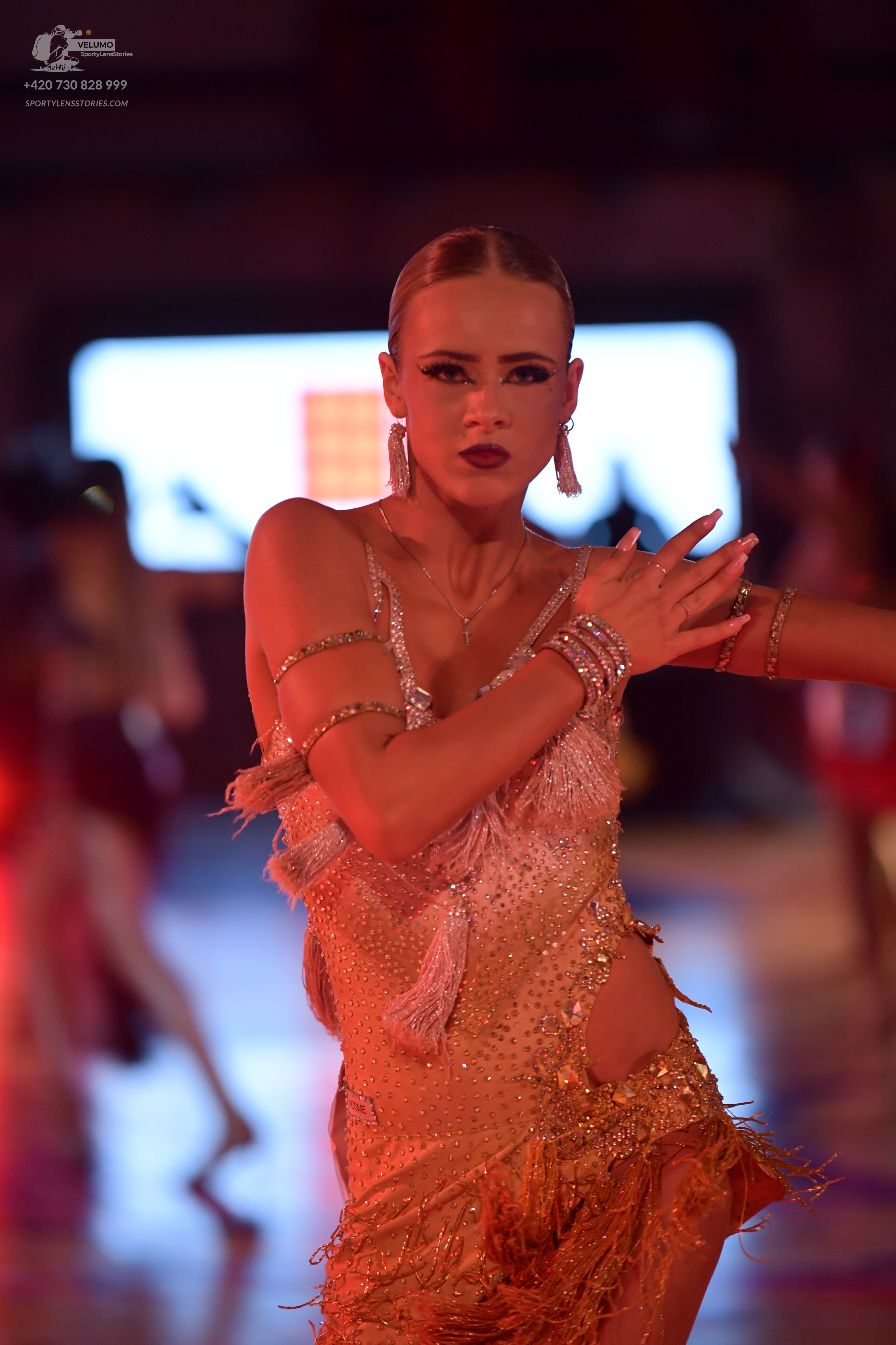 Dancesport competitor: Female dancer: gold/champagne Latin dance dress with sequins, fringe, and cut-ou