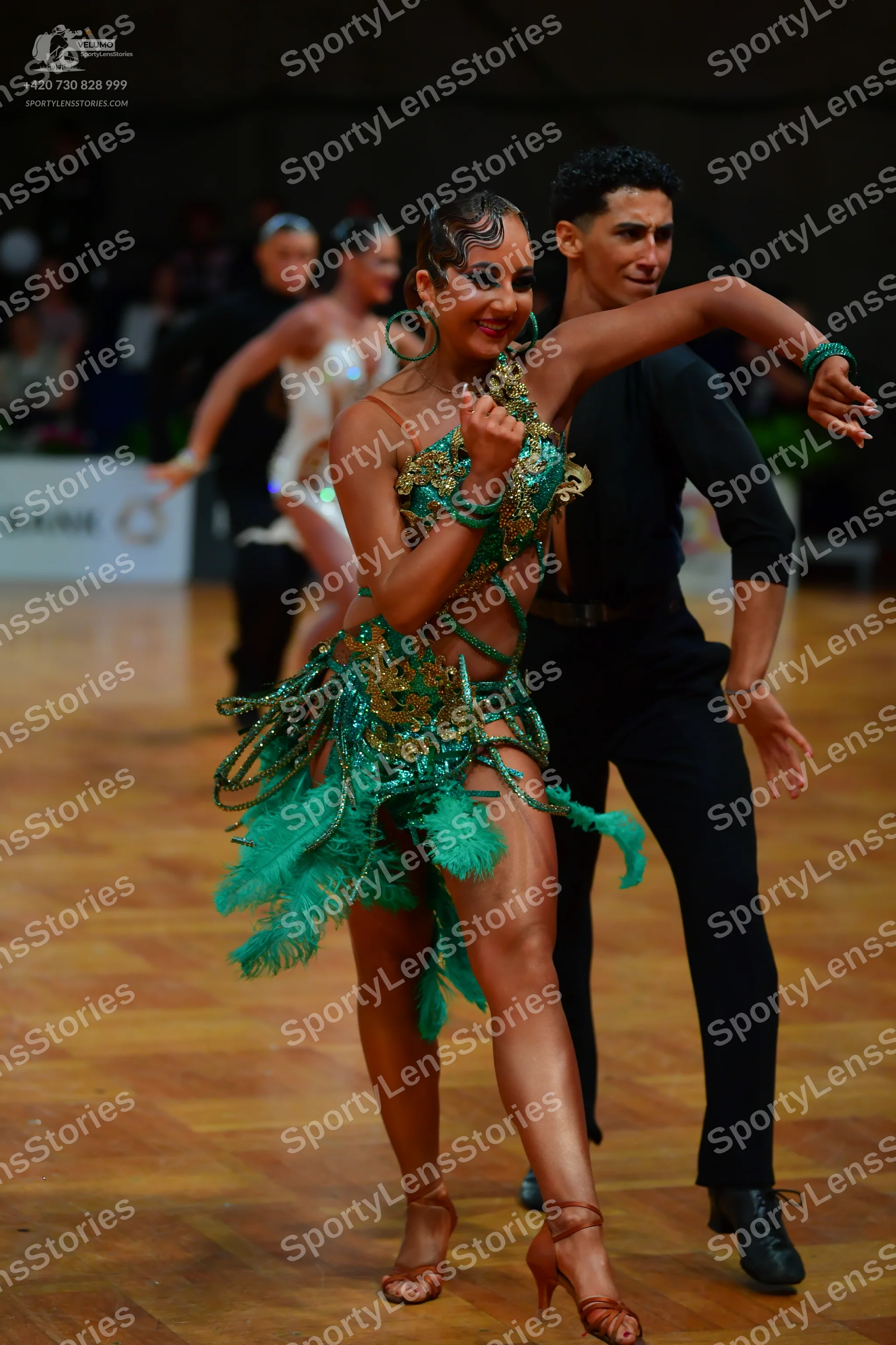 Dancesport competitor: Lead female dancer: emerald green Latin dance dress with gold sequin embellishme
