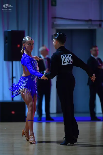Dancesport competitor #232: Female dancer: bright blue Latin dance dress with long sleeves, sequins, and fri
