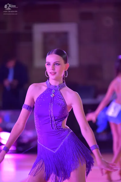 Dancesport competitor: Female dancer: purple latin dress with rhinestones and fringe, matching armbands